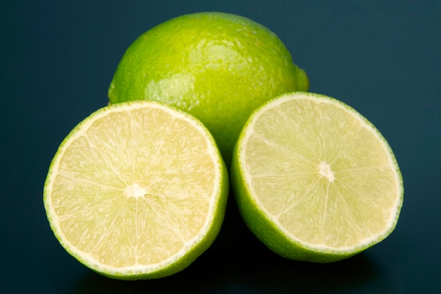 Tagliare gli agrumi di limone verde su sfondo blu. Cibo sano e vitaminico