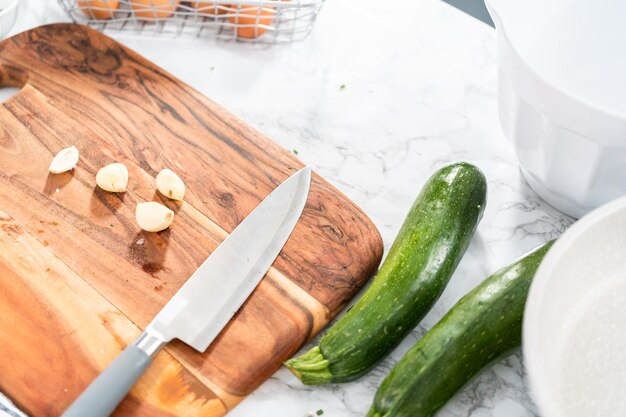 Tagliare gli ingredienti su un tagliere di legno per fare le torte di zucchine.