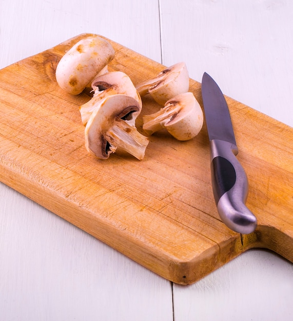 Tagliare i funghi su una tavola di legno e un coltello.