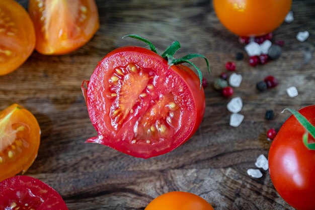 Tagliare i pomodori rossi e gialli su un tagliere di legno scuro, salare e pepare in grani