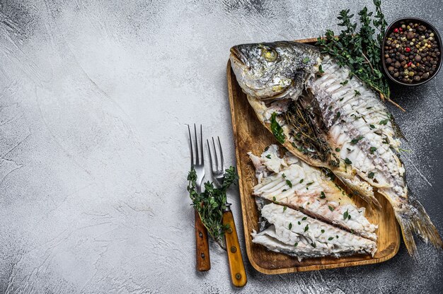 Tagliare il pesce dorado dell'orata al forno in un vassoio di legno