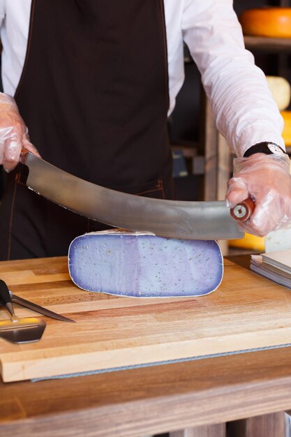 Tagliare il pesto di gouda lavanda, formaggio viola in drogheria, primo piano, verticale