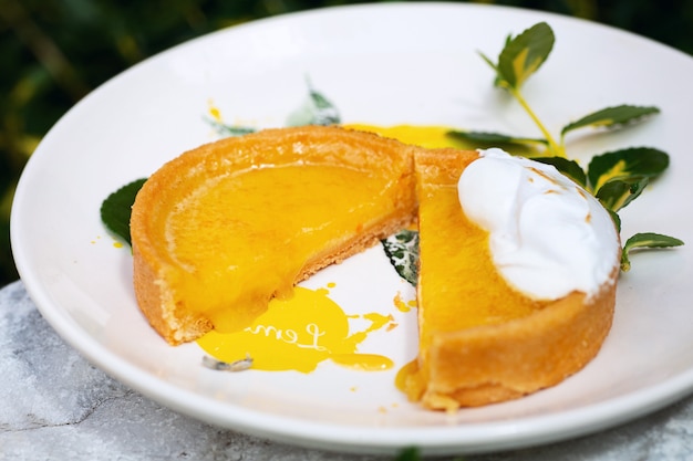 Tagliare il tortino di agrumi sul piatto bianco decorato con limone dipinto e fiore bianco su di esso