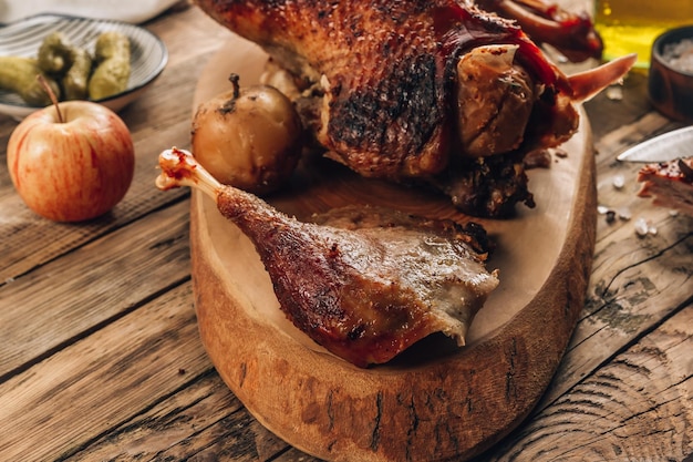 Tagliare l'anatra arrosto e le mele per una cena festiva su uno sfondo di legno rustico Foto selettiva