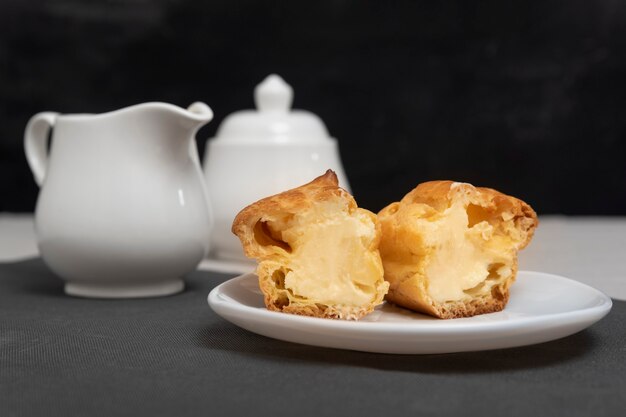 Tagliare l'eclair fatto in casa con ripieno all'interno. Dolci nel piatto. Cuocere per il tè.