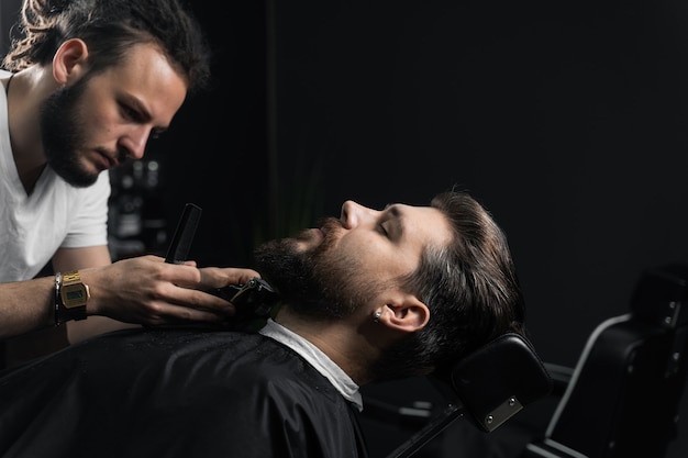 Tagliare la barba con una macchina da barba. Pubblicità per barbiere e salone di bellezza maschile.