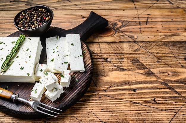 Tagliare la feta al formaggio con rosmarino su un tagliere di legno.