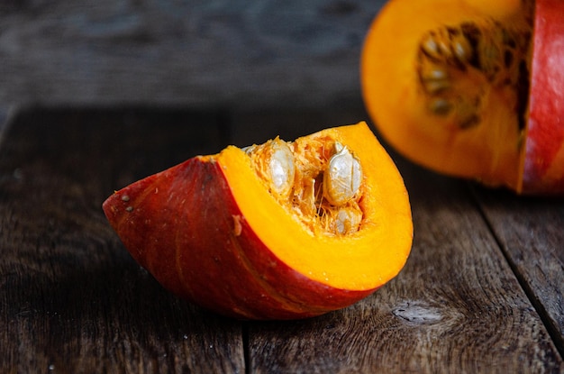 Tagliare la zucca su un tavolo di legno. Cucinare in cucina.