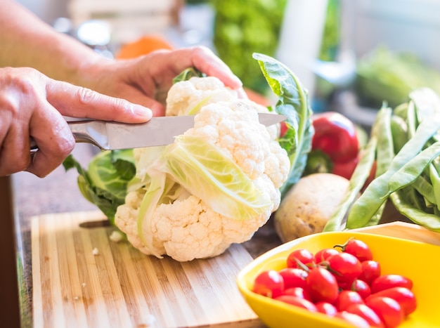 Tagliare un cavolfiore in cucina Le mani di una signora anziana tagliano e puliscono ogni tipo di verdura