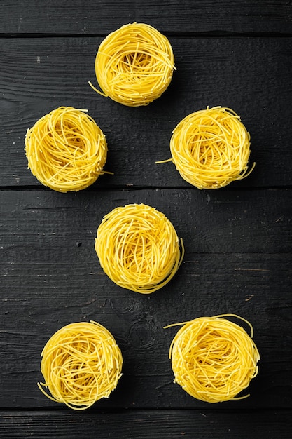 Tagliarini di pasta all'uovo fatta in casa di semola di grano duro su fondo di legno nero vista dall'alto piatto