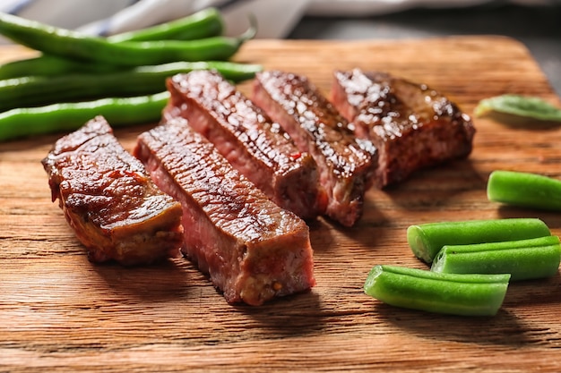 Tagliata di bistecca alla griglia con fagiolini su tavola di legno