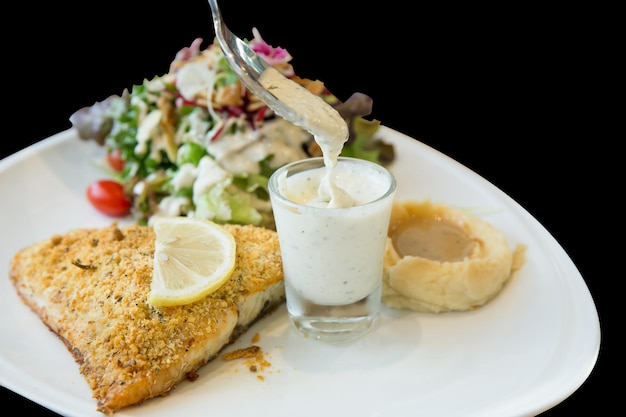 Tagliata di bistecca di branzino alla griglia con insalata su fondo nero isolato