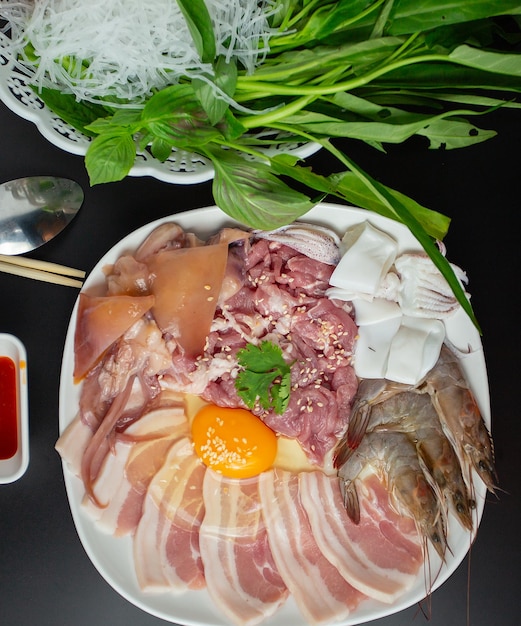 Tagliata di maiale crudo uova di pollo fresche e verdure fresche Il cibo tailandese Isaan 'chim chum' è un famoso piatto tailandese con una salsa piccante