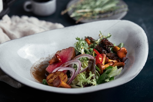 Tagliata di manzo con verdure. Primo piano, scuro, grigio.