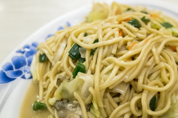 Tagliatella cinese fritta in un piatto sul tavolo