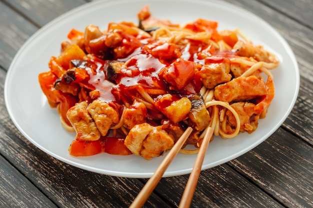 Tagliatella del Udon con il pollo e le verdure in una fine bianca del piatto su