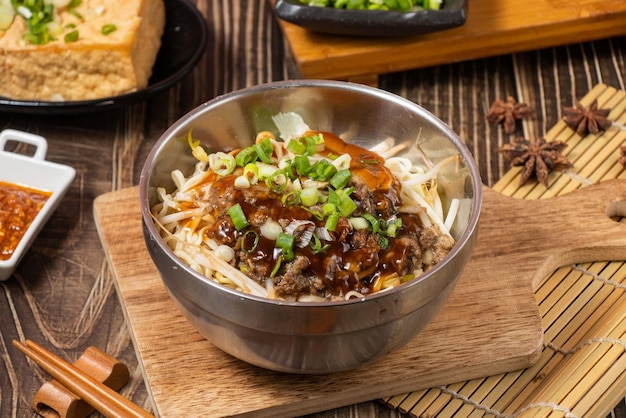 Tagliatella di pasta secca saporita in una ciotola d'acciaio isolata sulla vista laterale della tavola di legno sul cibo di Taiwan della tavola