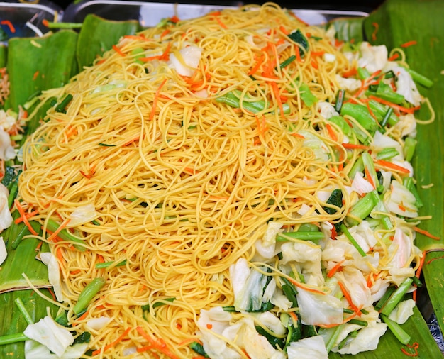 Tagliatella gialla fritta con la verdura sulla foglia della banana.