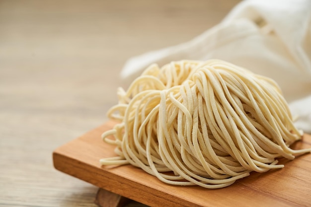 tagliatella ramen cruda in piatto di legno sul fondo della tavola di legno. ramen all'uovo fresco tagliatelle in legno backgro