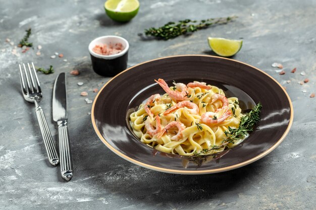 Tagliatelle ai frutti di mare con gamberi alla griglia, besciamella e timo, fettuccine. Cibo italiano. Concetto di pesce dieta sana. Vista dall'alto.