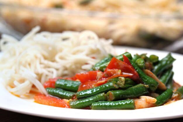 Tagliatelle al curry di fagiolini lunghi su un piatto bianco