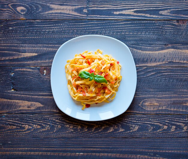 Tagliatelle al pomodoro e basilico, fatte in casa, su un tavolo di legno,