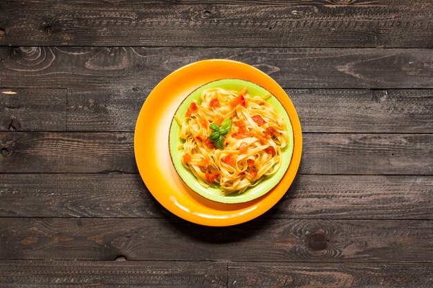 Tagliatelle al pomodoro e basilico, fatte in casa su un tavolo di legno