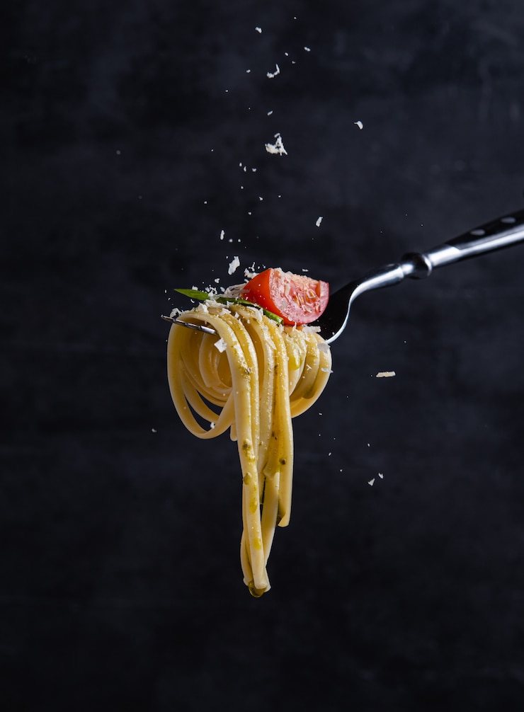 Foto tagliatelle al pomodoro e pesto sulla forchetta. cibo italiano. sfondo scuro