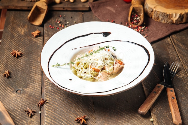 Tagliatelle al salmone con parmigiano sul tavolo di legno