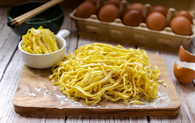 Tagliatelle all'uovo con farina sul tagliere di legno