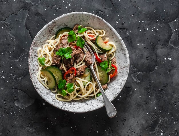 Tagliatelle all'uovo con peperone di manzo e zucchine su uno sfondo scuro vista dall'alto