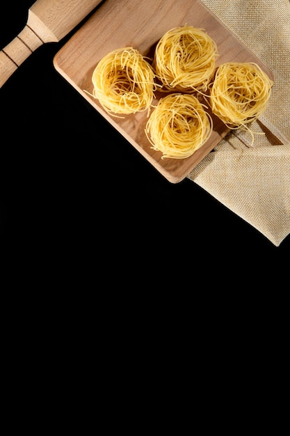 Tagliatelle arrotolate di pasta italiana su sfondo di pietra nera Foto di alta qualità