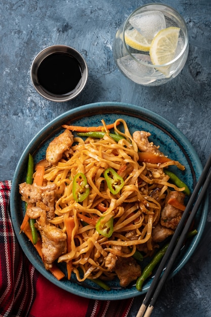 Tagliatelle asiatiche con carne di maiale in salsa teriyaki, con fagiolini, carote e funghi shiitake.