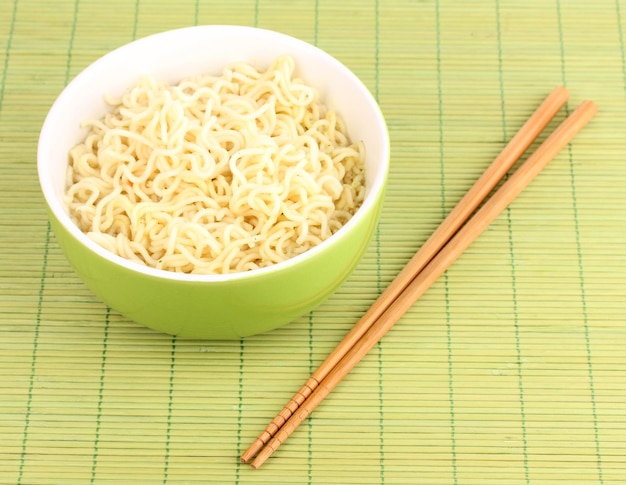 Tagliatelle asiatiche in ciotola sulla stuoia di bambù