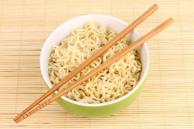 tagliatelle asiatiche in una ciotola su un tappetino di bambù