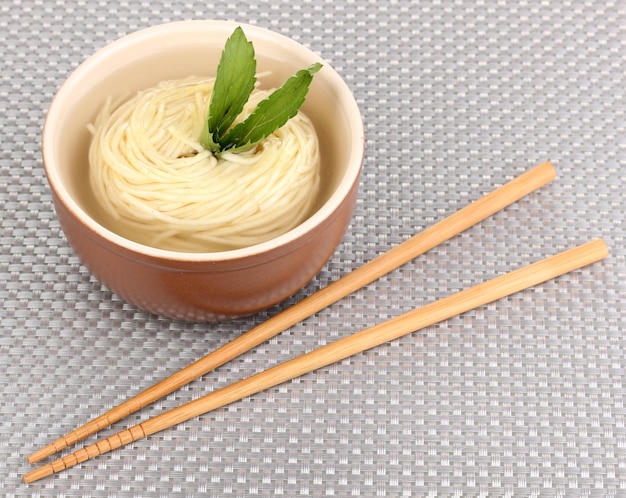 tagliatelle asiatiche in una ciotola sul tappeto grigio