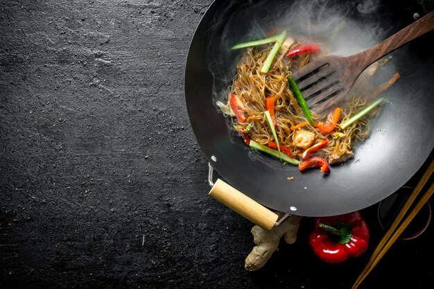 Tagliatelle cinesi di cellophane wok calde in padella con una spatola