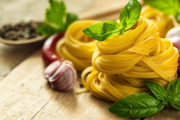 Tagliatelle con basilico, pepe, aglio e prezzemolo su tavola di legno da vicino con spazio copia