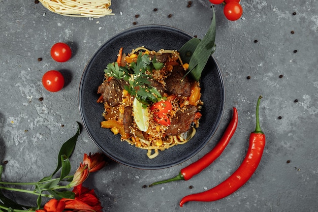 Tagliatelle con carne di vitello e verdure su un tavolo grigio.