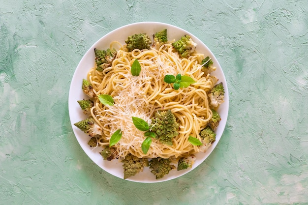 Tagliatelle con cavolfiore romanesco (broccoli) su un tavolo verde.