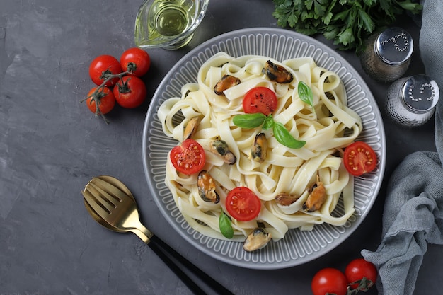 Tagliatelle con cozze e pomodorini su un piatto grigio