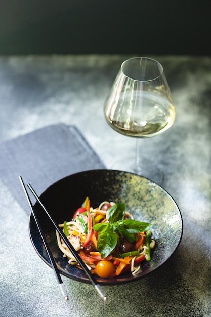 Tagliatelle con frutti di mare e verdure su sfondo scuro. Cibo asiatico.