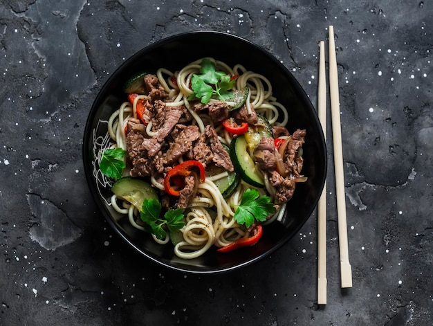 Tagliatelle con manzo bollito e verdure su uno sfondo scuro vista dall'alto