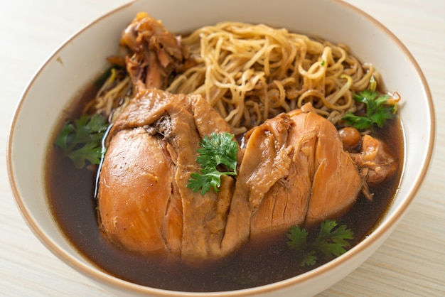 Tagliatelle con pollo brasato in una ciotola di zuppa marrone - Stile di cibo asiatico