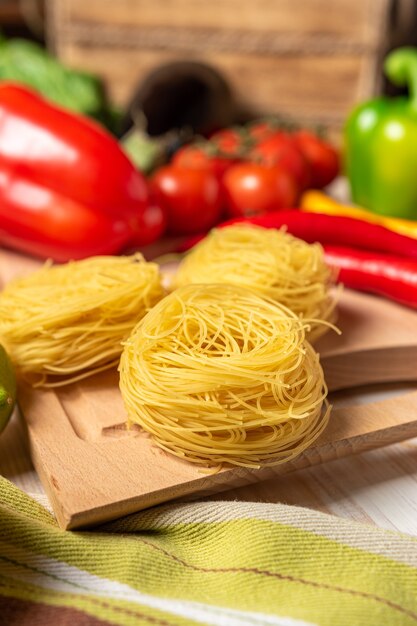 Tagliatelle con verdure colorate e spezie sulla tavola di legno.