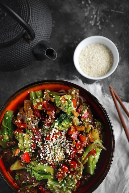 Tagliatelle con verdure e carne su sfondo scuro, cibo asiatico, vista dall'alto, messa a fuoco selettiva