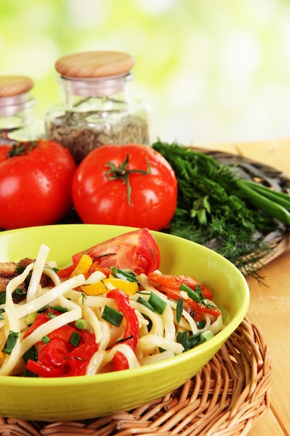 Tagliatelle con verdure su wok su vegetazione sfocata