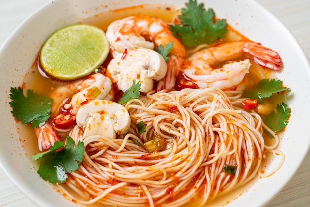 tagliatelle con zuppa piccante e gamberetti in una ciotola bianca (Tom Yum Kung) - Stile di cibo asiatico