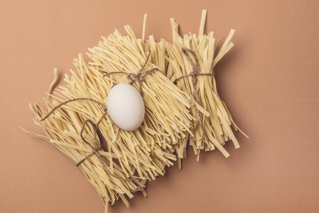 Tagliatelle di grano essiccate fatte in casa con uovo crudo su sfondo marrone chiaro Vista dall'alto orizzontale