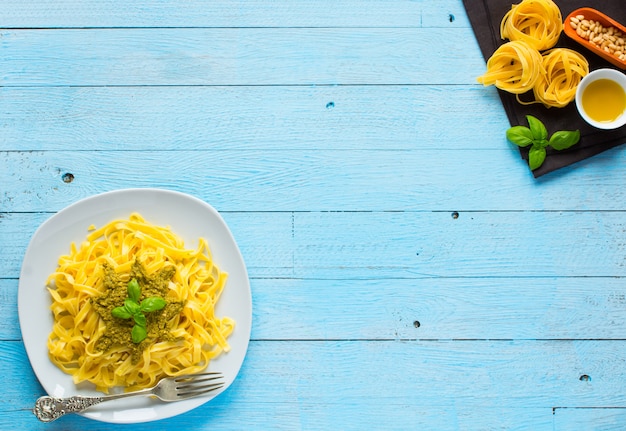 Tagliatelle di pasta al pesto e altre verdure su un tavolo di legno